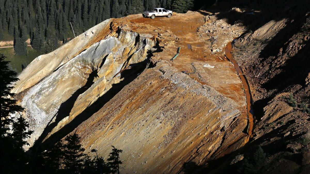 In 2015, wastewater flows down a trough, right, from a blowout at the Gold King Mine near Silverton, Colo.