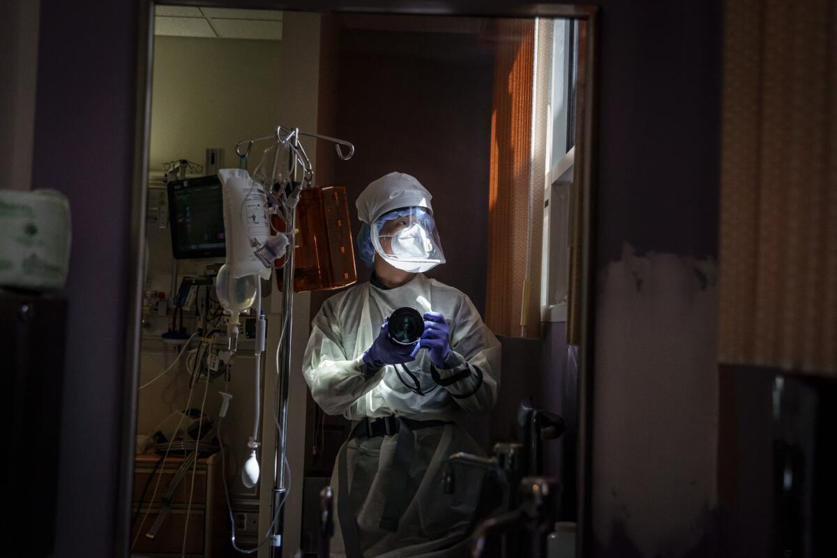 A self-portrait of Times photographer Marcus Yam wearing PPE and an air-purifying respirator in a hospital.