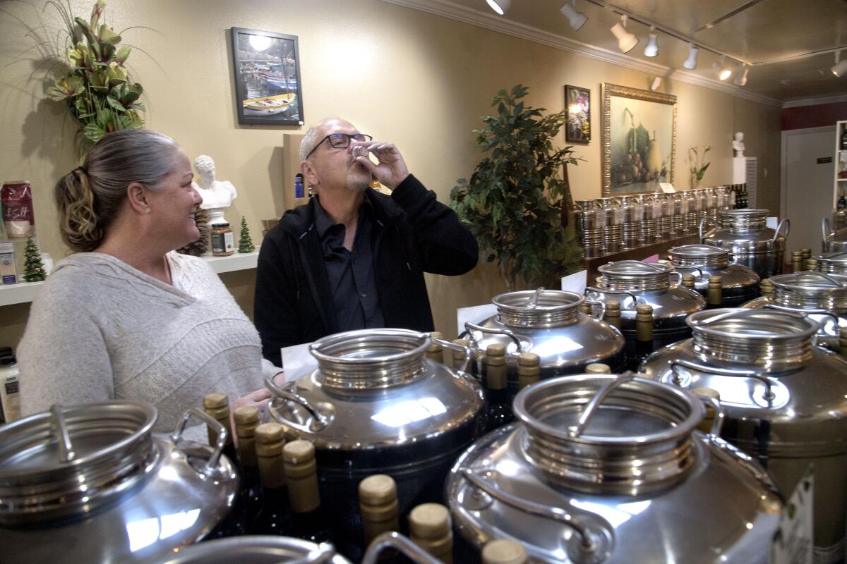Owner Julie Brawner and customer Rob Feuerstein, sampling oil, at Oliver's Olive Oils.