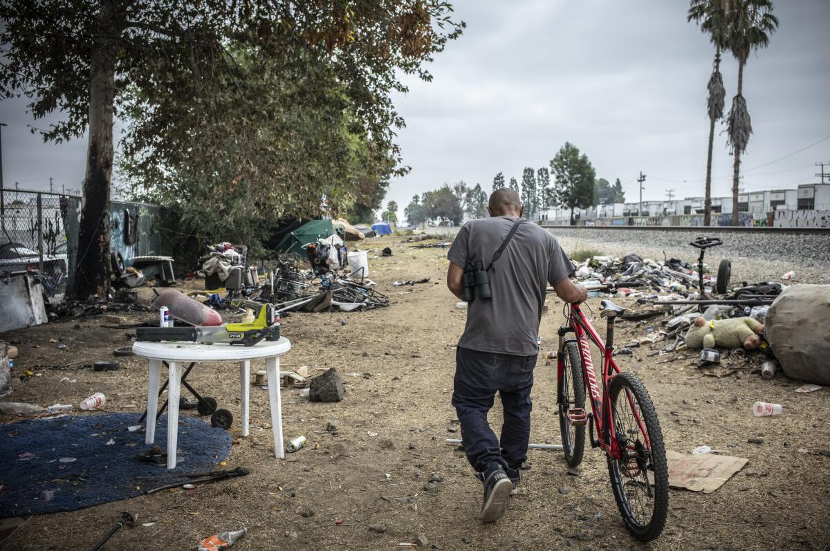 Jose Quinonez walks his bike near his shelter at a homeless encampment in Northridge.