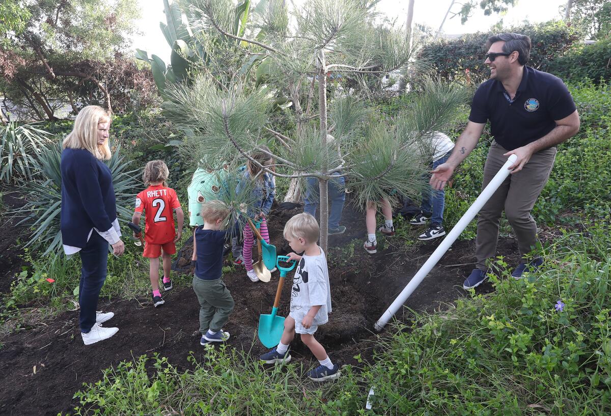 Mayor Sue Kempf and city arborist Matthew Barker join kids in planting a celebratory pine tree.
