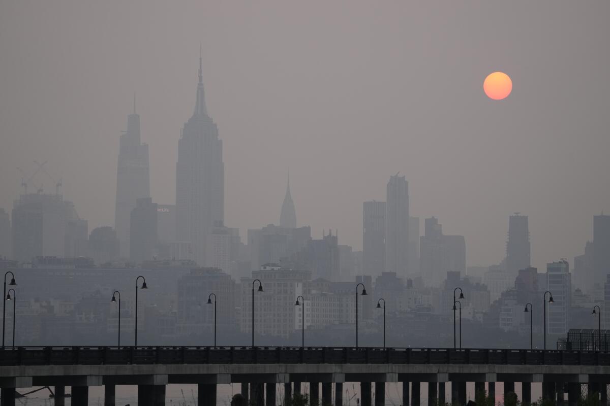 The sun rises over a hazy New York City skyline as seen from Jersey City, N.J.