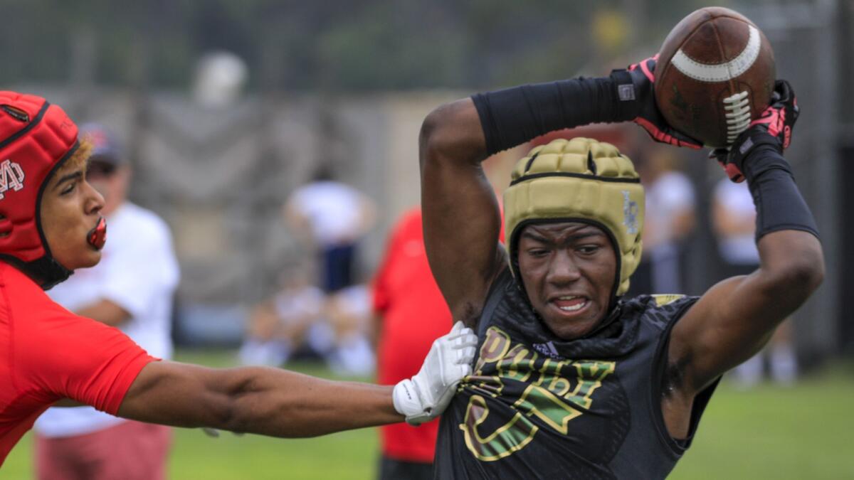 Long Beach Poly wide receiver Ramil Brown, right, hauls in a pass over his head against a Mater Dei defender during the Mission Viejo passing tournament at Mission Viejo High School on Saturday.
