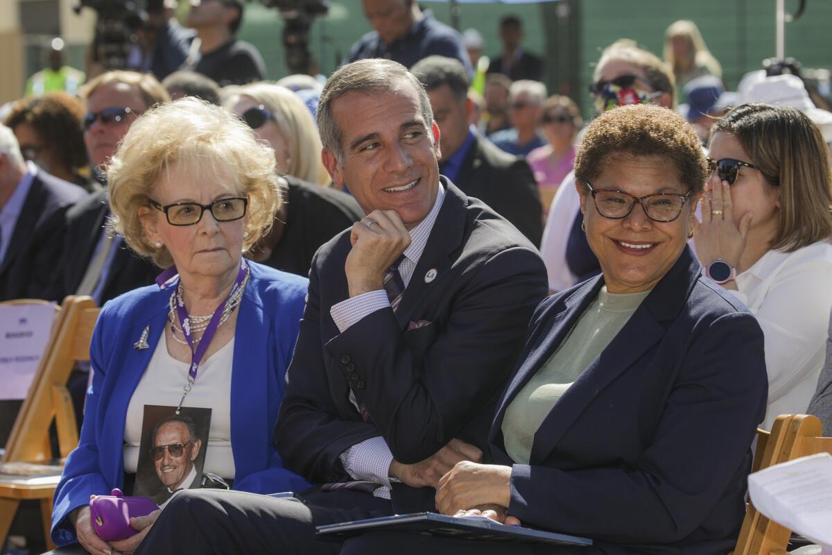 A man and two women sit among a crowd.