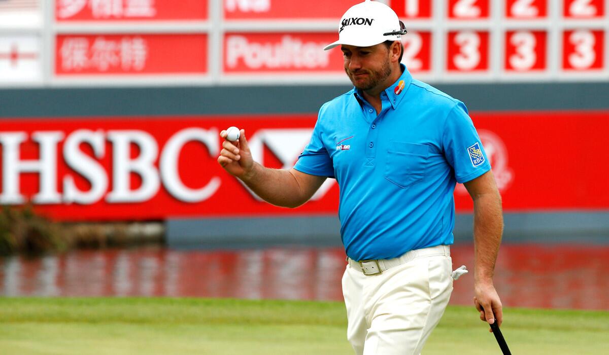 Graeme McDowell walks off the 18th green after shooting a second consecutive five-under-par 67 on Friday at the HSBC Champions tournament.