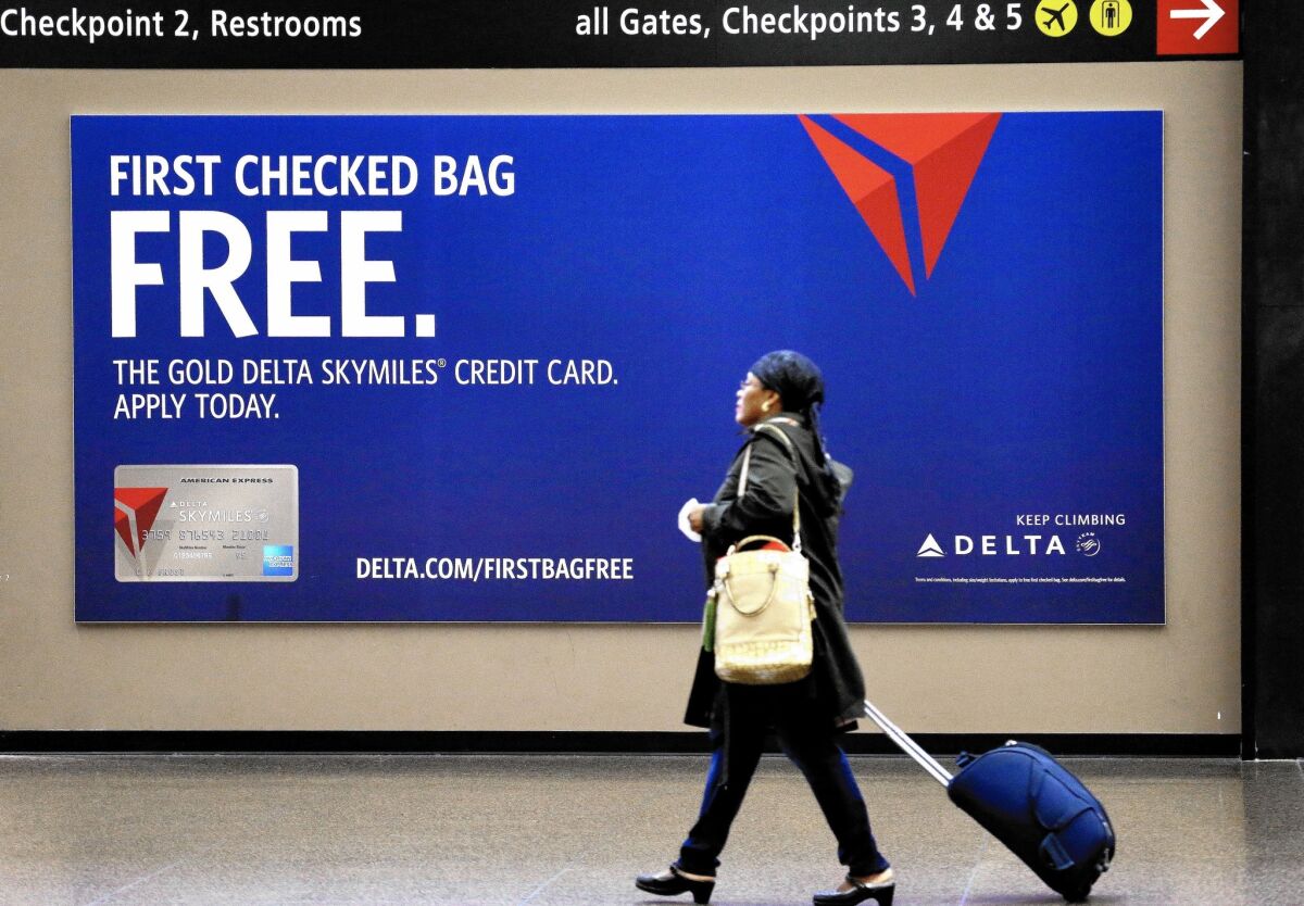 Delta Air Lines’ privacy policy shows what consumers are up against when trying to figure out how their personal info will be used. Above, a traveler walks past a sign advertising a Delta credit card at Seattle-Tacoma International Airport in SeaTac, Wash.