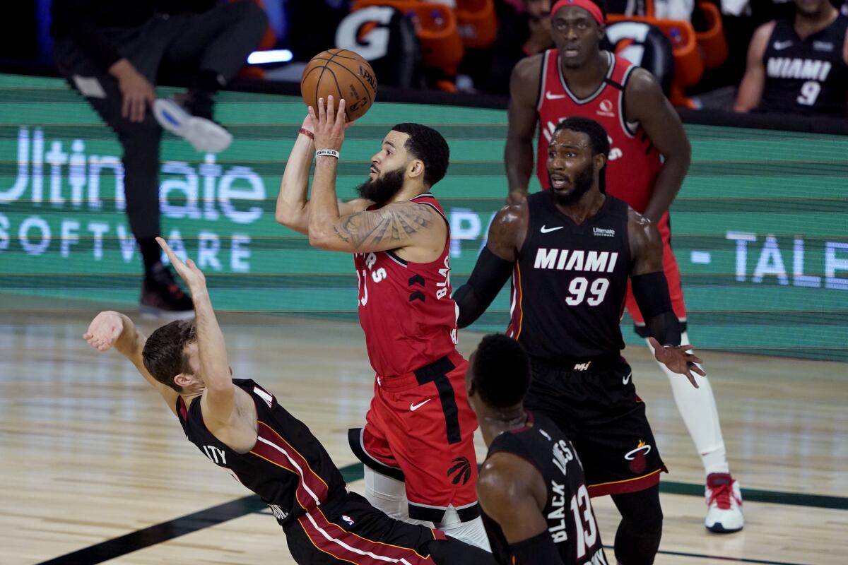 Toronto Raptors' Fred VanVleet shoots as Miami Heat's Goran Dragic tries to draw the offensive foul.