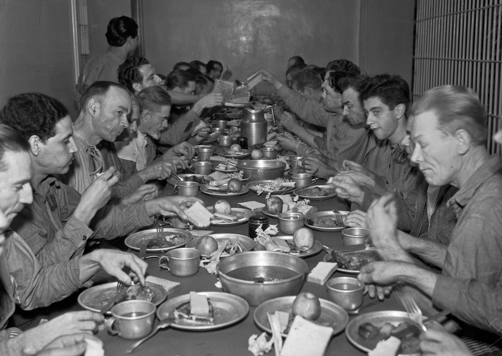 Men sit and dine on two sides of a long table.