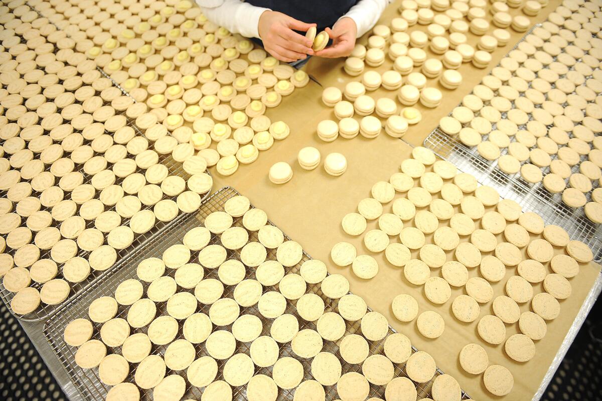 Desiree Ramos sandwiches the pairs of macaron shells after piping at Bottega Louie's pastry kitchen in downtown Los Angeles.