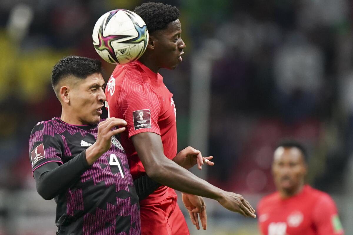 Jonathan David, de Canadá, disputa un balón con Edson Álvarez, de México.