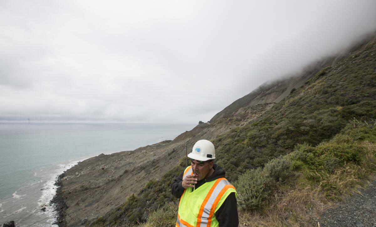 Caltrans resident engineer Rick Silva surveys the area above Highway 1 where a massive landslide obliterated the road. (Brian van der Brug / Los Angeles Times)