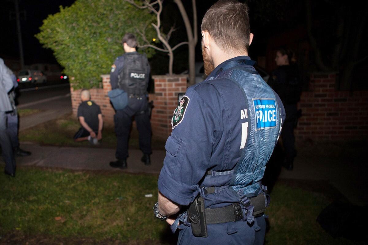 Australian Federal Police officers detain a suspect in Sydney after Australia's largest-ever counterterrorism raids.