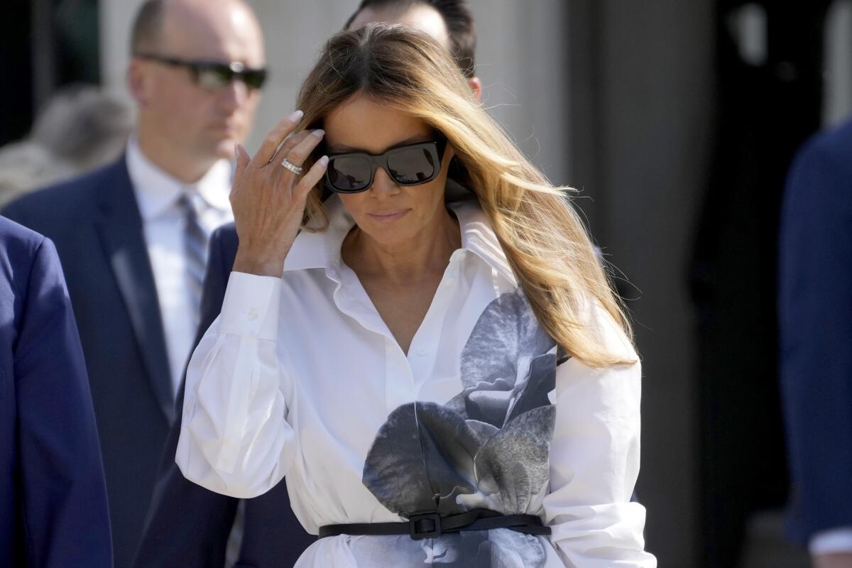 Former first lady Melania Trump, wearing sunglasses, walks outside