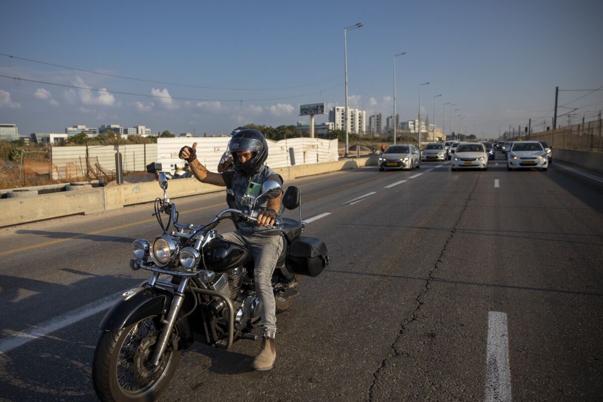 A convoy of cars slow down the traffic as they staged demonstration against the Health Ministry's "green pass" restrictions, on Ayalon highway, in Tel Aviv, Israel, Sunday, Oct. 3, 2021. Israel restricted its coronavirus "green pass" on Sunday to allow only those who have received a COVID-19 booster or recently recovered to enter indoor events, sparking protests by opponents who say the system is a form of forced vaccination. (AP Photo/Oded Balilty)
