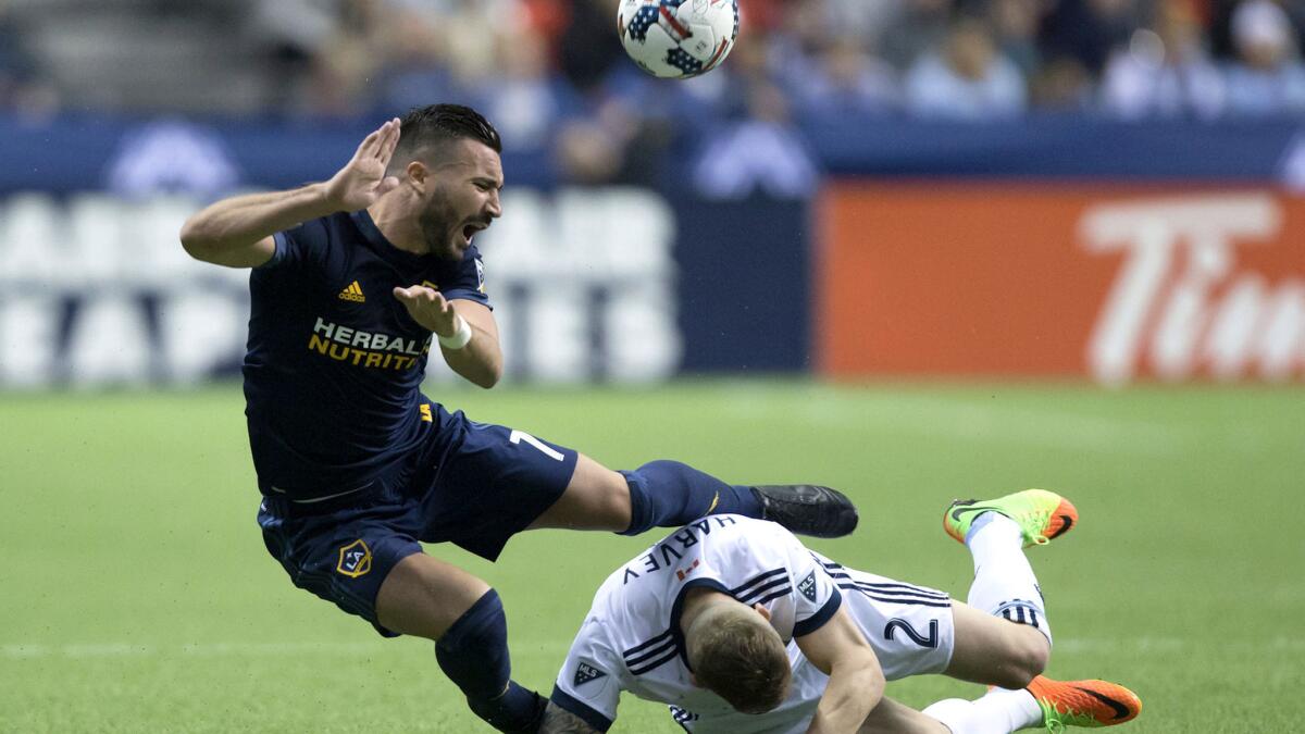 Galaxy midfielder Romain Alessandrini (7) and Whitecaps defender Jordan Harvey (2) collide while vying for the ball during the second half Saturday night in Vancouver.