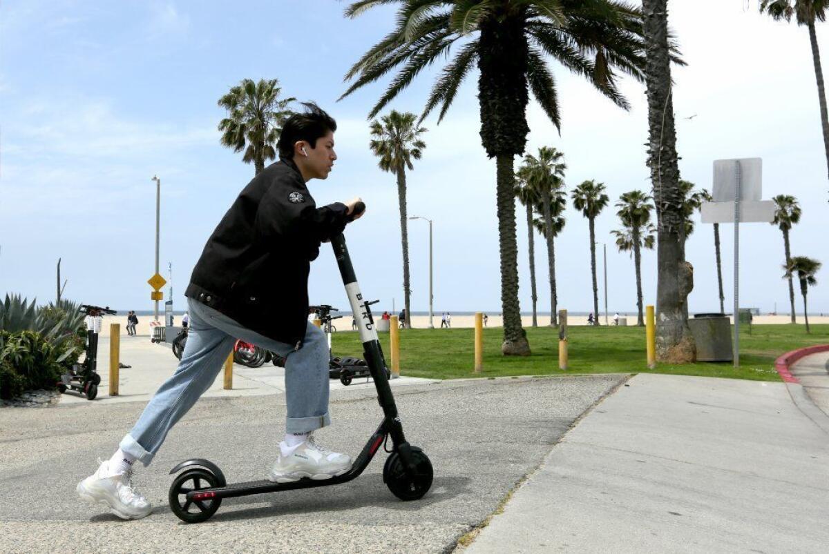 A Ninebot Bird scooter is ridden near the beach in Venice.