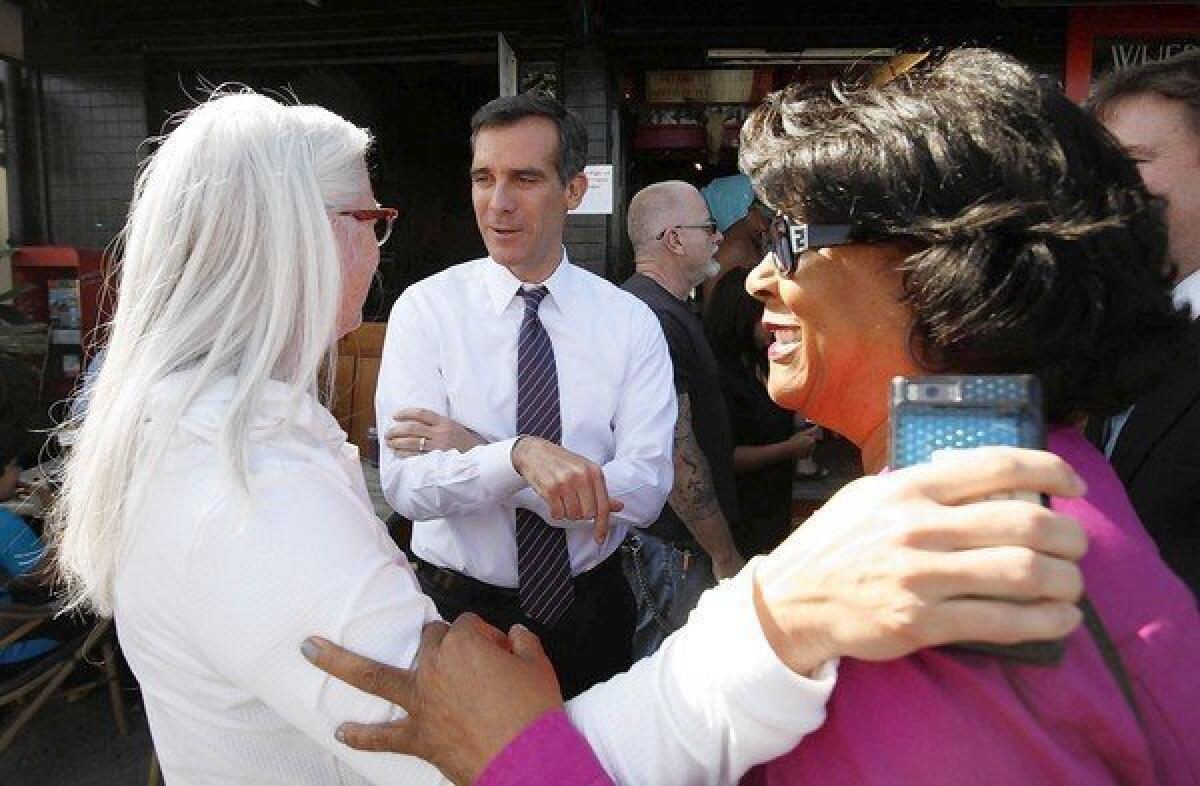 Then-Los Angeles City Councilman Eric Garcetti talks with supporter Kim Norris, left, and then-Councilwoman Jan Perry during a campaign stop while running for mayor.
