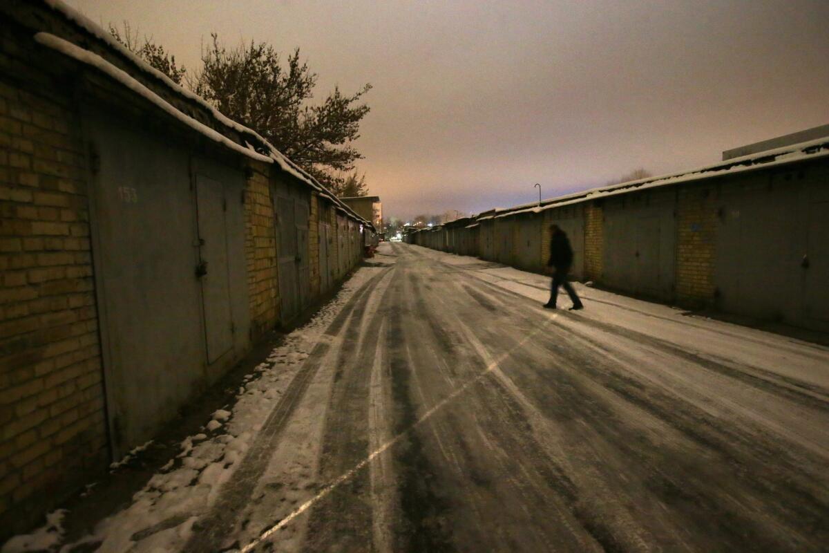 A Ukrainian volunteer walks past garages, some of which are serving as a storehouse for humanitarian aid for Ukrainian soldiers.
