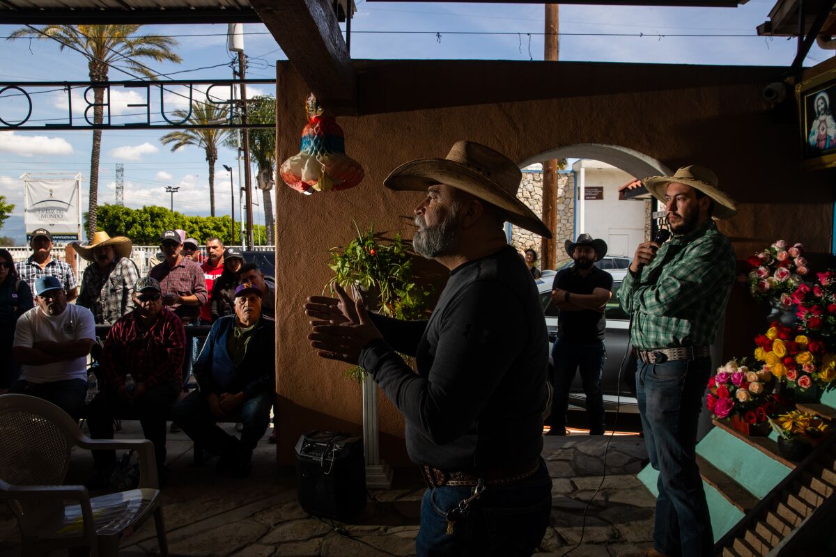 Two men in cowboy hats speak at a public meeting.
