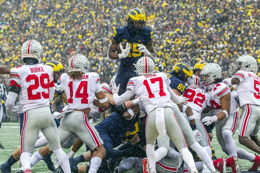 Michigan running back Hassan Haskins leaps over Ohio State defenders for a second-quarter touchdown Nov. 27, 2021.
