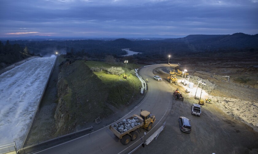 Helicopters and large dump trucks placed rocks on the damaged emergency spillway at Oroville Dam on Monday evening.