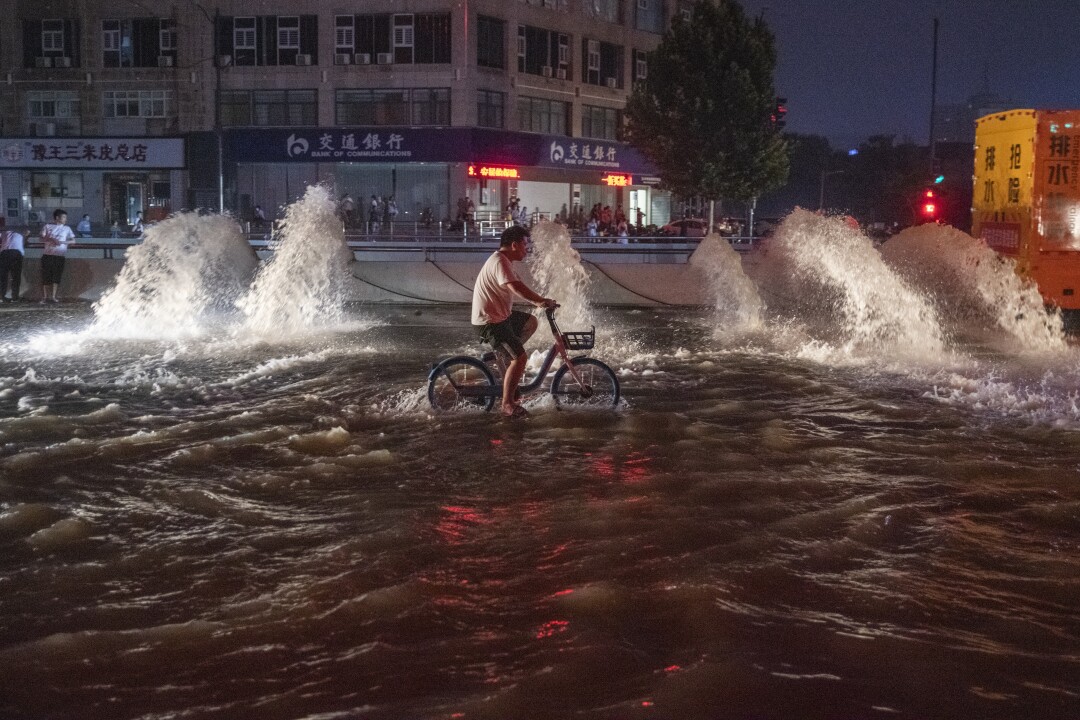 A man rides a bicycle in floodwaters 