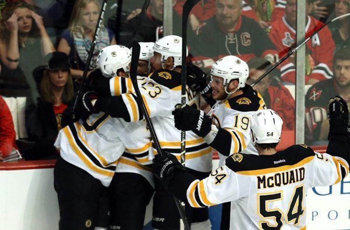 Bruins teammates celebrate with Daniel Paille, left, after he scored the winning goal in overtime against the Blackhawks on Saturday night in Chicago.