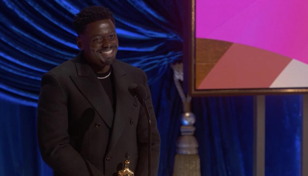 Daniel Kaluuya smiles and holds his Oscar