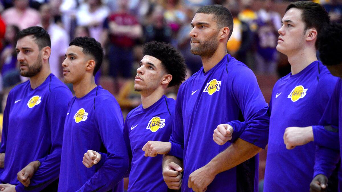 Stephen Zimmerman, far right, and his Lakers teammates lock arms during the national anthem before the start of a preseason game against the Timberwolves.