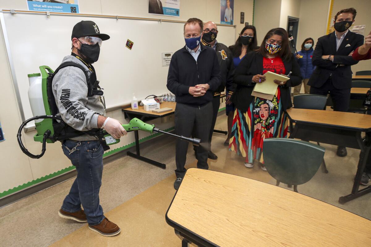 School plant manager Sergio Ruiz demonstrates the use of a electrostatic sprayer 