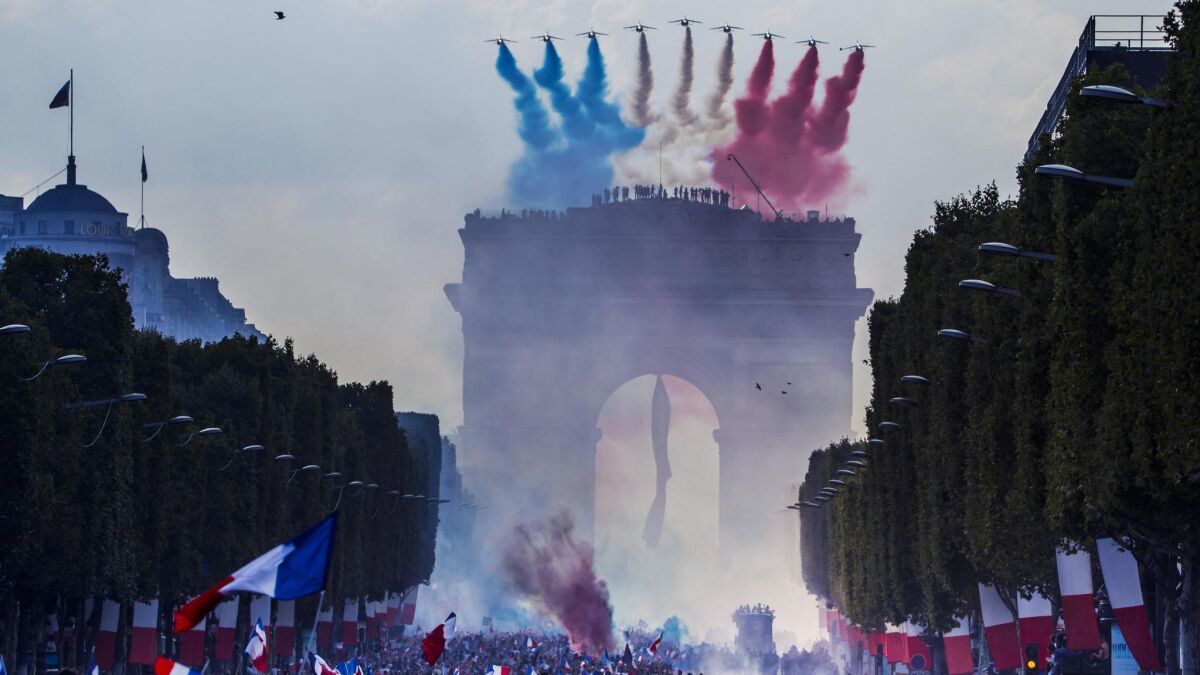 The 'Patrouille de France' military aircrafts pass over the Champs Elysees avenue as French supporters greet their national soccer team players during a parade down the Champs-Elysee avenue in Paris.