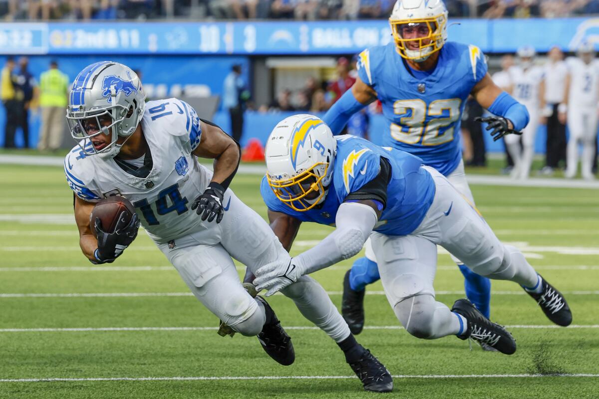  Lions  receiver Amon-Ra St. Brown (14) slips the tackle of  Chargers linebacker Kenneth Murray Jr. (9).