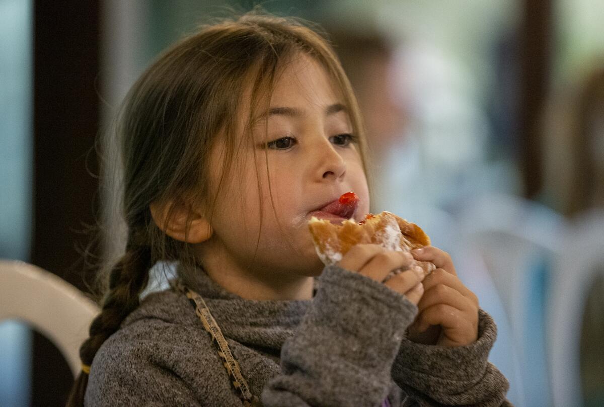 Maddie Kent, 6, with Girl Scout Troop 9390 out of Huntington Beach, licks the jelly out of a sufganiyot, an Israeli donut.