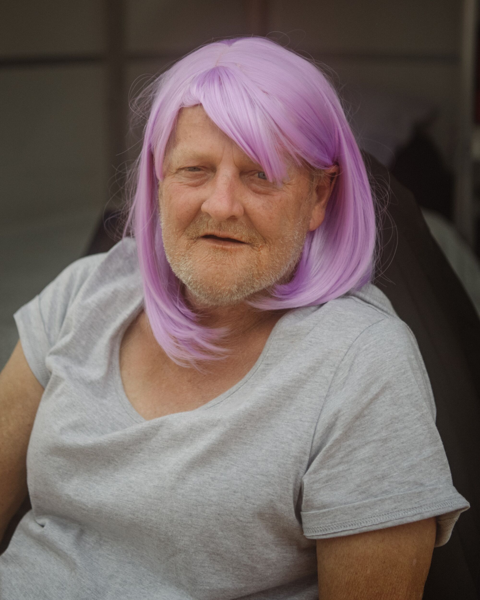 Portrait of a person wearing a light purple wig and a gray T-shirt