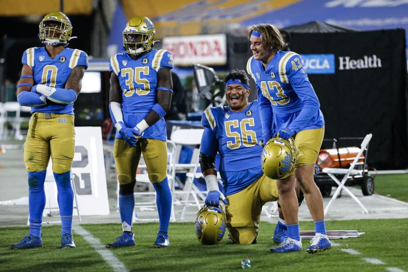 UCLA offensive line Atonio Mafi kneels next to teammates during a game