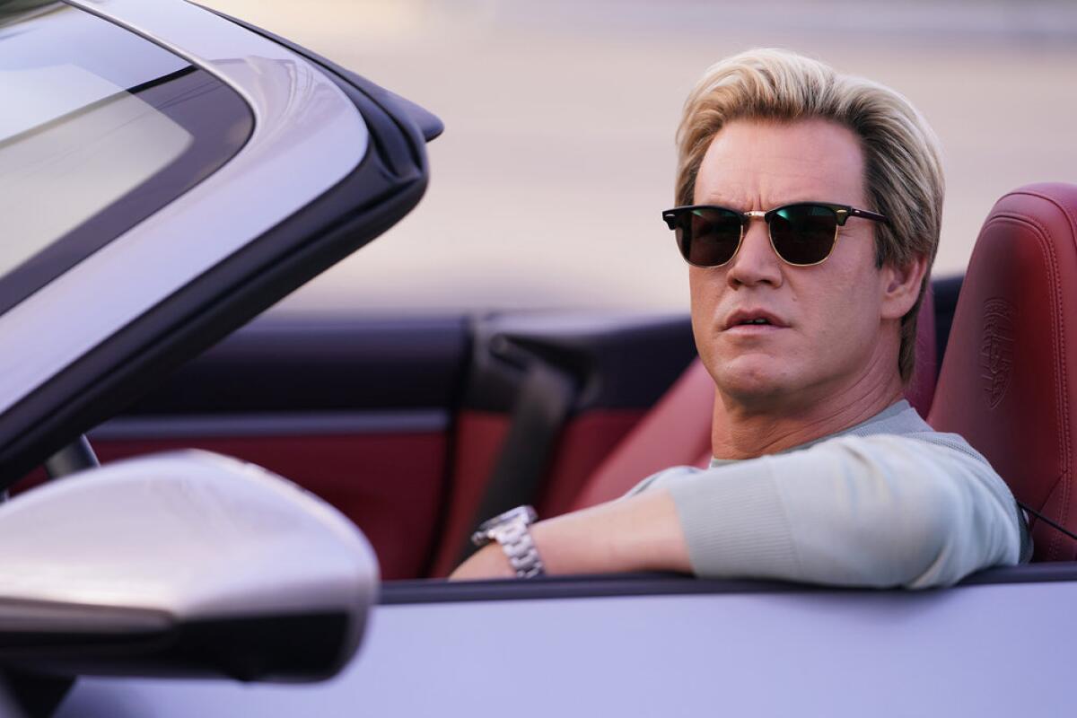 A man in sunglasses behind the wheel of a convertible