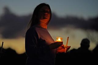 A mourner attends a candlelight vigil for the victims of this week's mass shootings, Saturday, Oct. 28, 2023, in Lisbon Falls, Maine. A gunman killed multiple people at the bowling alley and a bar in nearby Lewiston, Maine, on Wednesday. The body of suspected shooter Robert Card was found not far from the site of the vigil. (AP Photo/Robert F. Bukaty)