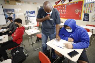 HAWTHORNE, CA - JULY 26: 11th grade student Justin Ake, right, is masked in the Math 2 class of teacher Cordell Haynes, left, as students attend the last two day's of summer school at Hawthorne High School in the South Bays Centinela Valley Union High School District which didn't reopen in the spring, and instead reopened for in-person summer instruction. The students are finishing 5 weeks of the summer school session. Various summer schools are in session, and some districts see them as a trial run for the fall when it comes to protocols like distancing and masking mandates. Hawthorne High School on Monday, July 26, 2021 in Hawthorne, CA. (Al Seib / Los Angeles Times).