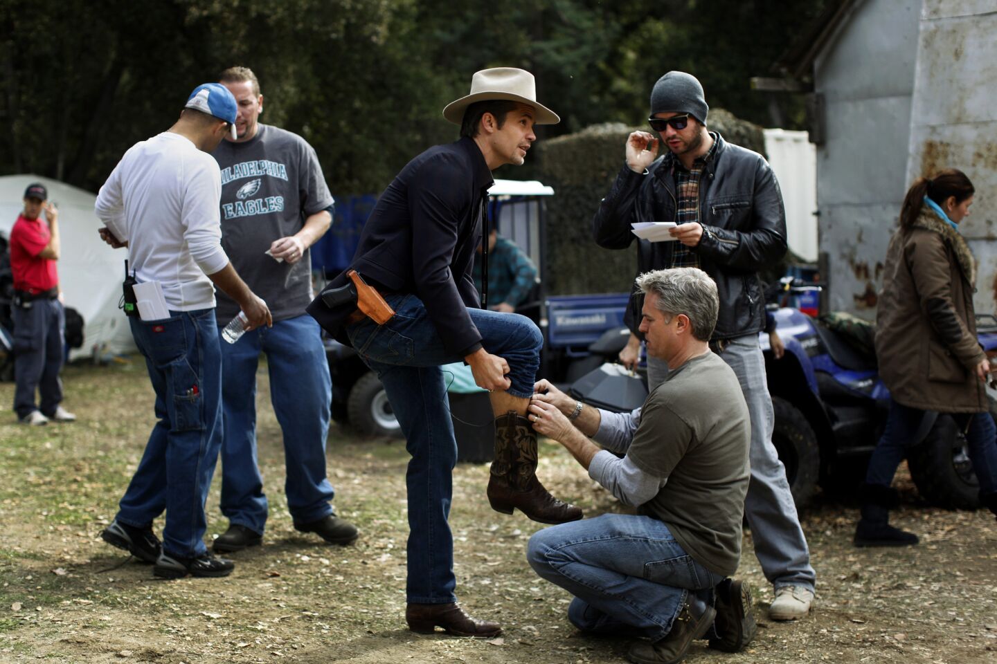 Actor Timothy Olyphant (in the cowboy hat) as Deputy U.S. Marshal Raylan Givens, is prepared for his microphone before shooting begins on the "Church of the Two-Stroke Jesus" set.