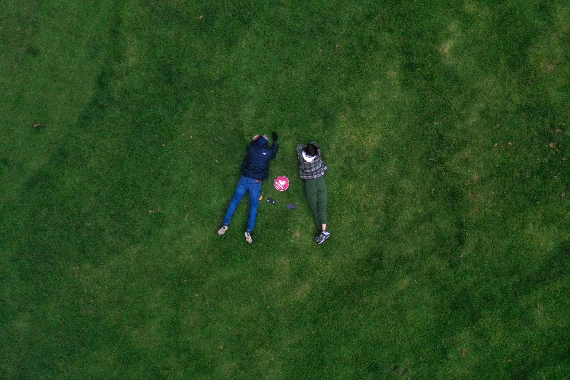 Two people lying next to each other in the grass at Holmby Park.
