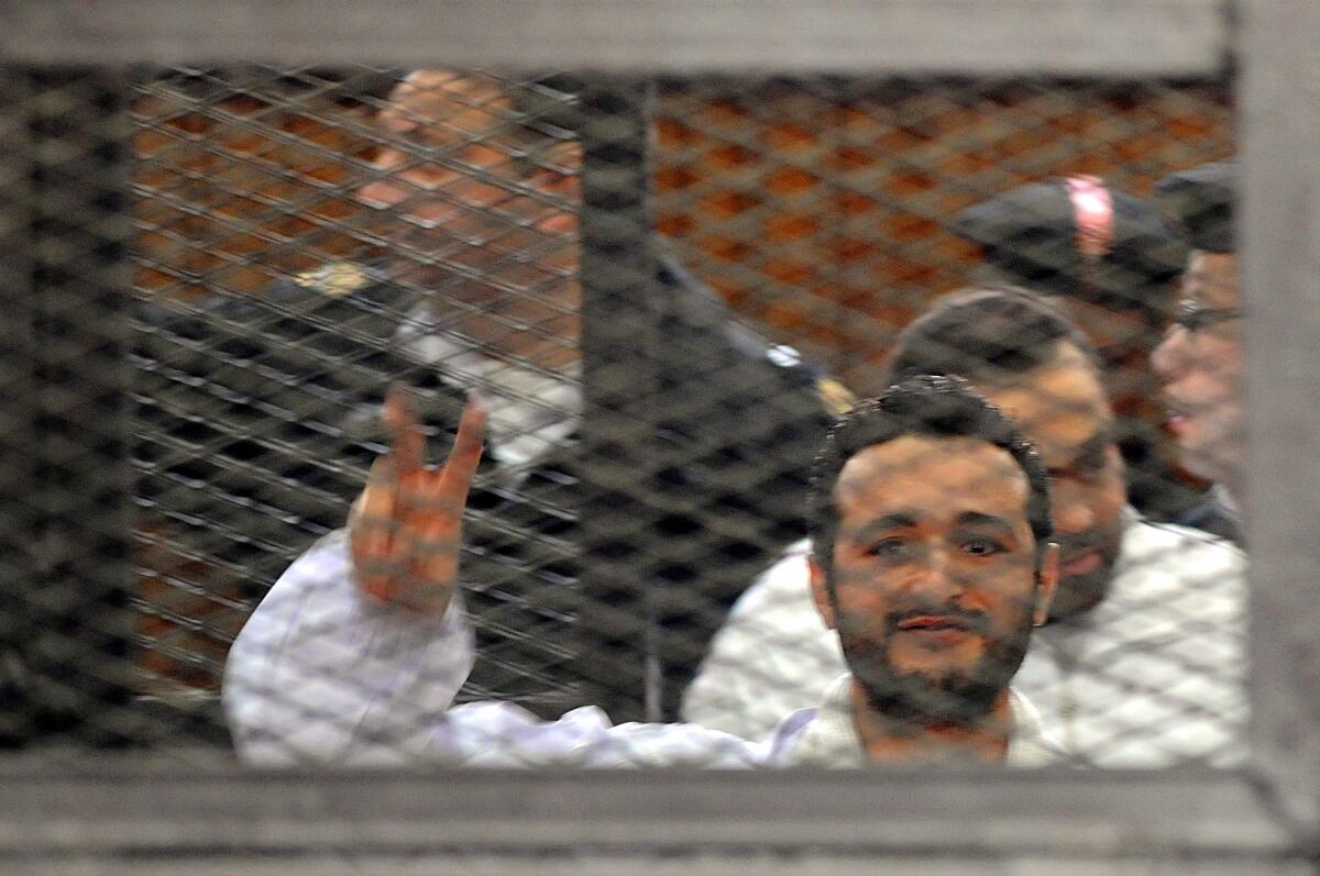 Egyptian activist Ahmed Douma signals to his supporters during his trial in Cairo.