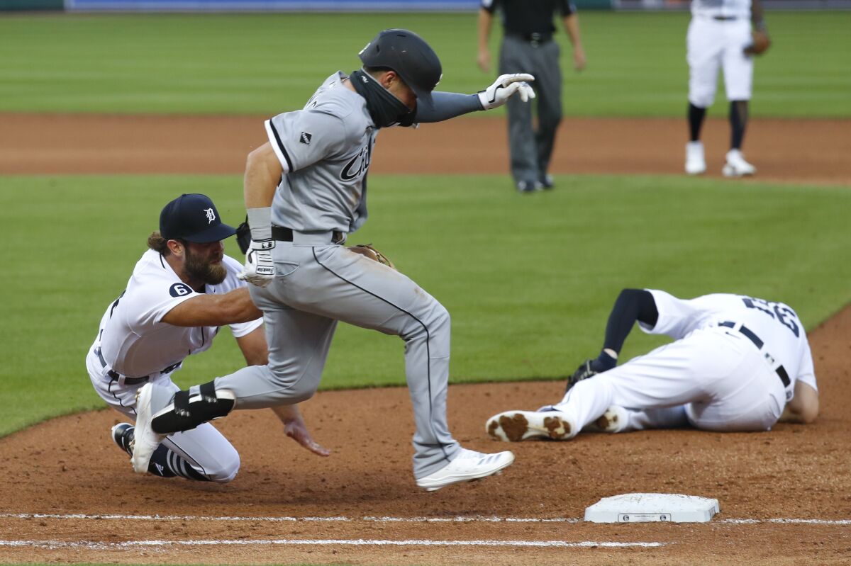 Detroit Tigers pitcher Daniel Norris, left, dives to tag out Chicago White Sox's Danny Mendick, center, as first baseman C.J. Cron (26) lies injured on the field in the fourth inning of a baseball game in Detroit, Monday, Aug. 10, 2020. (AP Photo/Paul Sancya)