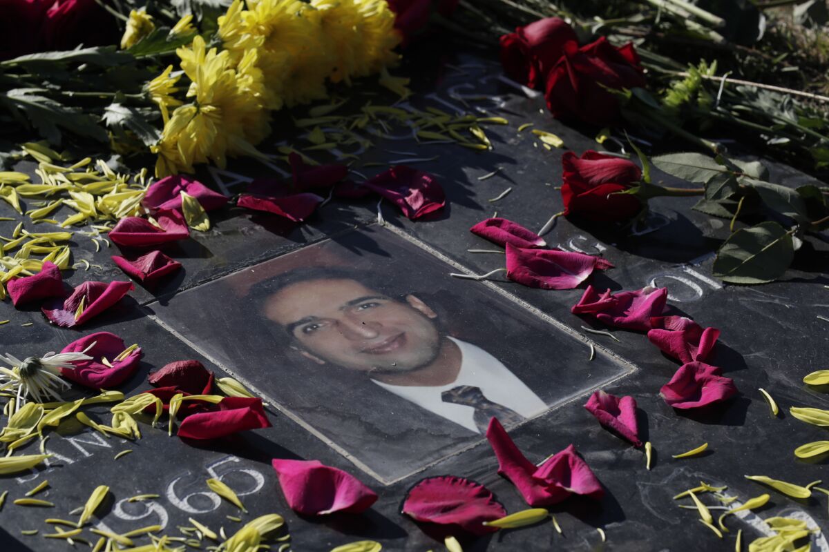 Flower petals surround a man's portrait on his gravestone