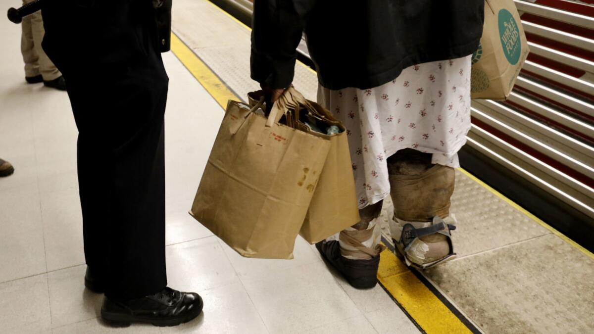 An LAPD officer speaks with Ken Adam, wearing a hospital gown, in the subway. (Francine Orr / Los Angeles Times)