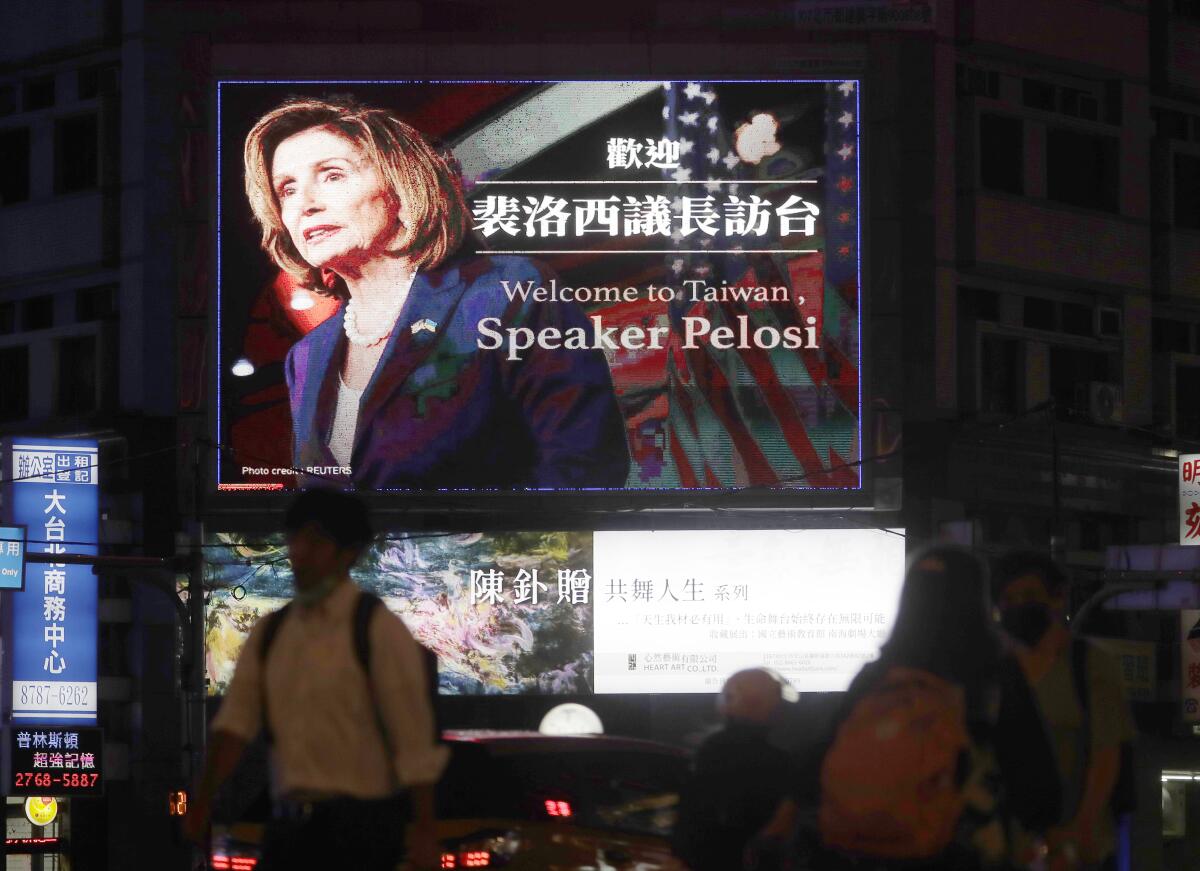 People walk past a billboard welcoming U.S. House Speaker Nancy Pelosi, in Taipei, Taiwan, Tuesday, Aug 2, 2022. U.S. House Speaker Nancy Pelosi was believed headed for Taiwan on Tuesday on a visit that could significantly escalate tensions with Beijing, which claims the self-ruled island as its own territory. (AP Photo/Chiang Ying-ying)