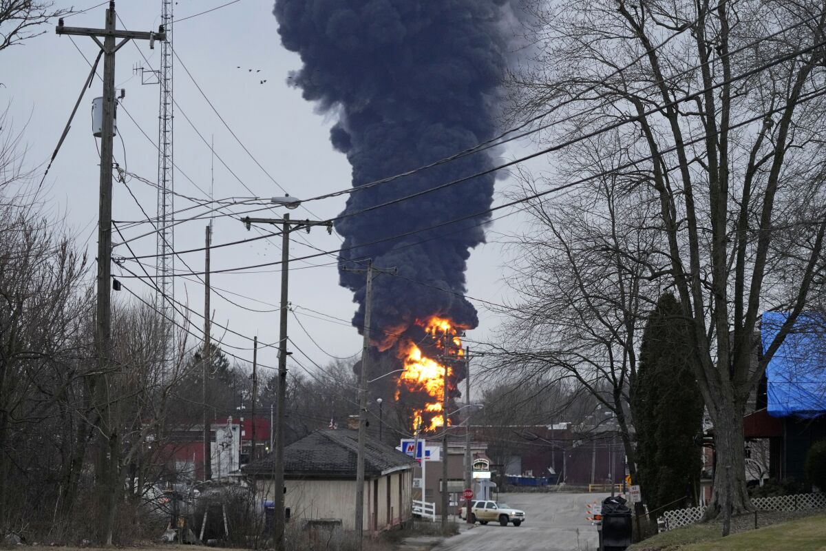A black plume of smoke rises from a fire in a small town