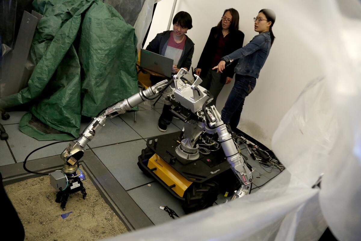 UCLA student Lionel Zhang, left, professor Veronica J. Santos and student Shengxin Jia talk about a minesweeping robot in one of the school's labs.