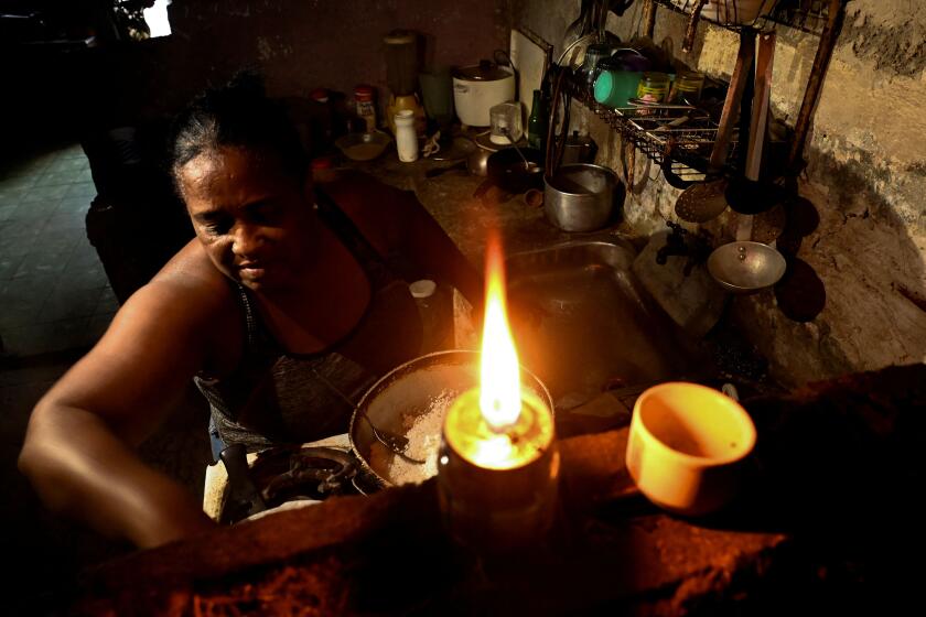 TOPSHOT - A woman cooks in her home without electricity in the aftermath of Hurricane Ian in Havana on September 29, 2022. - The National Electric System (SEN) collapsed on Tuesday, leaving the island blacked out due to the damage caused by the powerful hurricane Ian, which caused the death of three people and severe damage in the western part of the country. (Photo by YAMIL LAGE / AFP) (Photo by YAMIL LAGE/AFP via Getty Images)