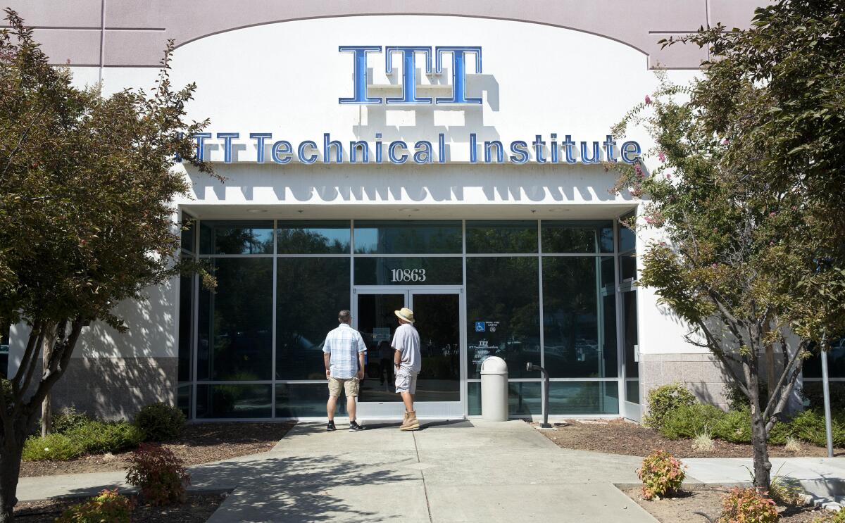 Two people stand outside a building with a sign reading ITT Technical Institute