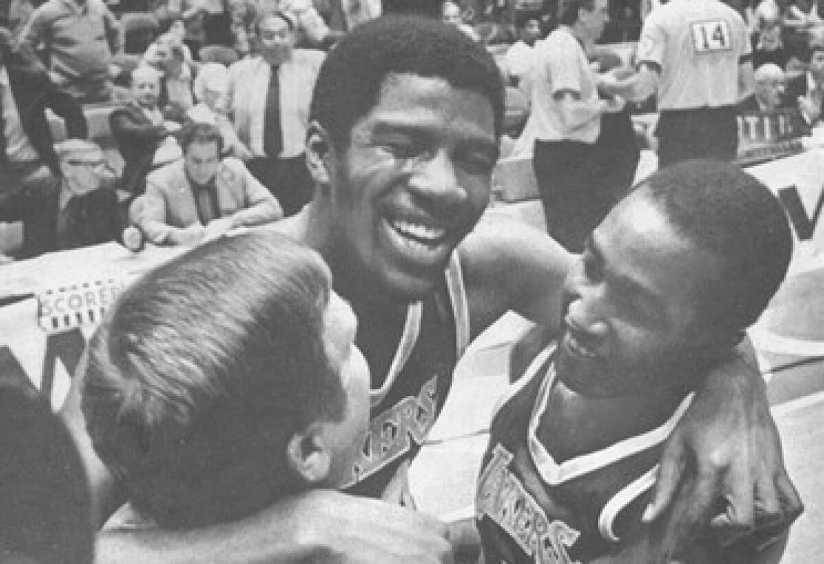 Magic Johnson, center, is embraced by trainer Jack Curran and teammate Butch Lee.